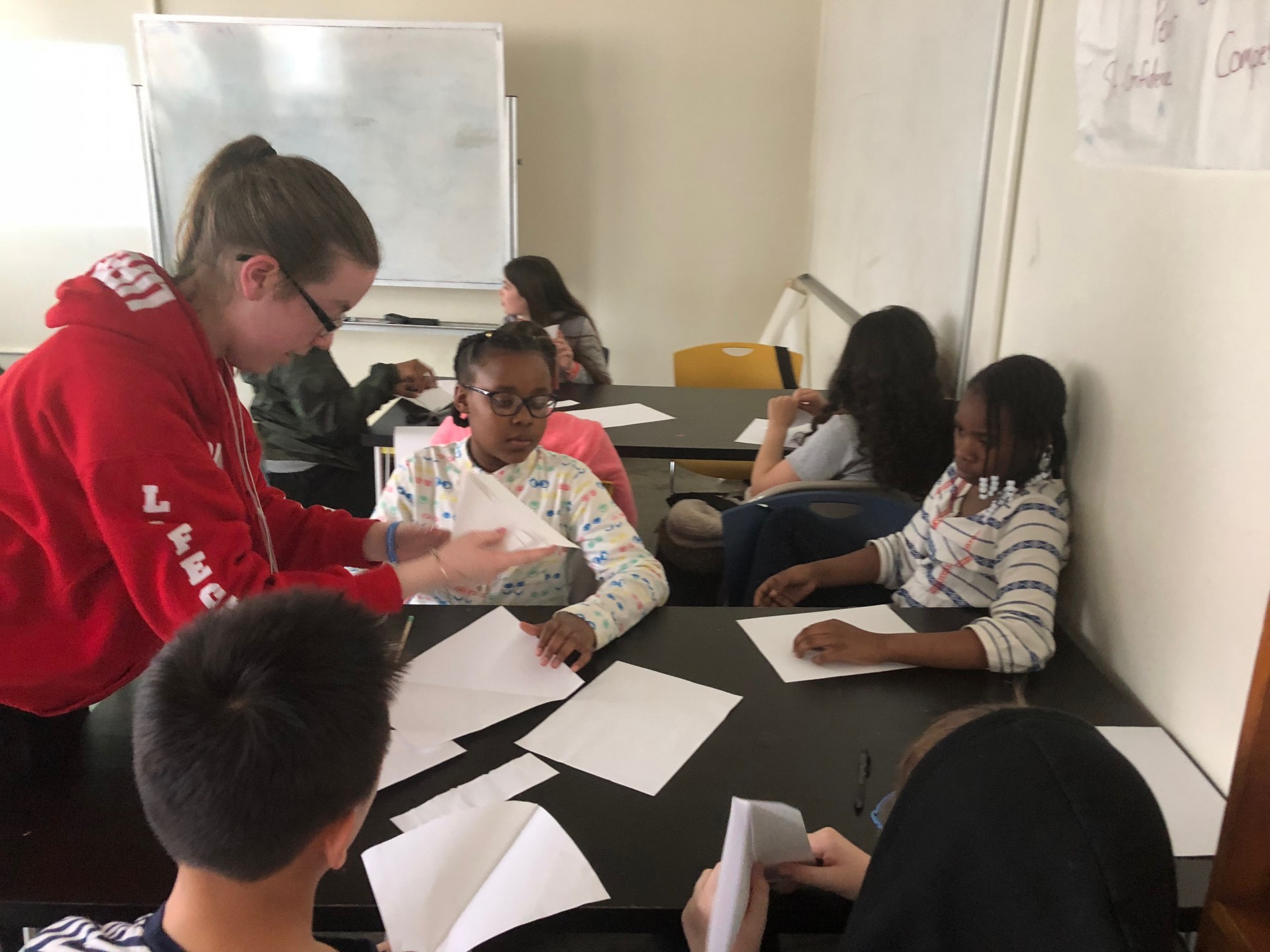 Stephanie working one on one with students, helping them make their origami hearts.