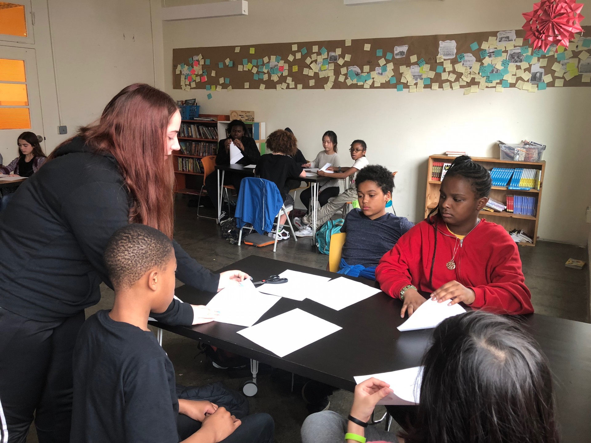 Mercedes working one on one with students, helping them make their origami hearts.